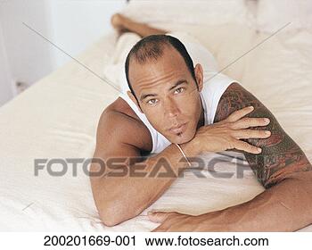 Stock Photography - man lying on bed, 
resting chin on 
hand, portrait. 
fotosearch - search 
stock photos, 
pictures, images, 
and photo clipart