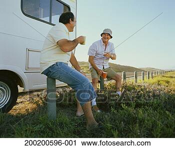 Stock Photography - senior man and 
man sitting on 
fence posts outside 
campervan, laughing. 
fotosearch - search 
stock photos, 
pictures, images, 
and photo clipart