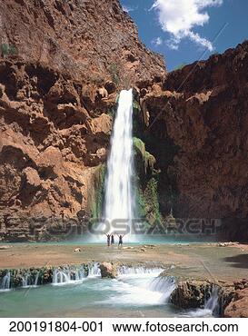 Stock Photography - three hikers standing 
below falls with 
arms lifted above 
heads. fotosearch 
- search stock 
photos, pictures, 
images, and photo 
clipart