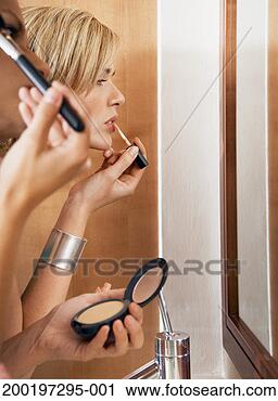 Stock Photography - two women applying 
make-up in mirror 
(focus on woman 
in background). 
fotosearch - search 
stock photos, 
pictures, images, 
and photo clipart