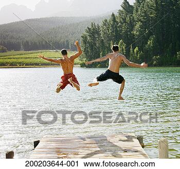 Stock Photography - two young men 
jumping off jetty 
into lake, rear 
view. fotosearch 
- search stock 
photos, pictures, 
images, and photo 
clipart