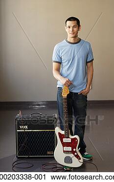 Stock Photography - young man with 
electric guitar 
standing beside 
amplifier, portrait. 
fotosearch - search 
stock photos, 
pictures, images, 
and photo clipart