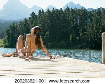 Stock Photography - young woman sunbathing 
on jetty by lake, 
rear view. fotosearch 
- search stock 
photos, pictures, 
images, and photo 
clipart