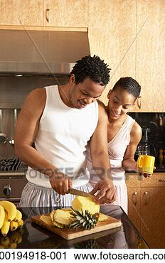 Stock Photography - young woman watching 
young man cut 
pineapple in domestic 
kitchen. fotosearch 
- search stock 
photos, pictures, 
images, and photo 
clipart