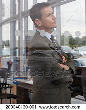 Stock Photography - businessman standing 
in car showroom, 
arms folded, view 
through glass. 
fotosearch - search 
stock photos, 
pictures, images, 
and photo clipart