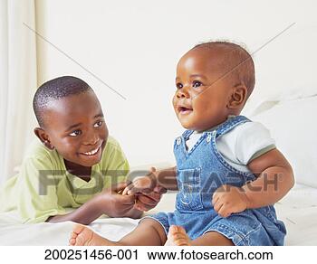 Stock Photography - boy (3-5) holding 
baby brother's 
(6-9 months) hand, 
smiling. fotosearch 
- search stock 
photos, pictures, 
images, and photo 
clipart