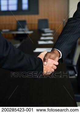Stock Photography - two businessmen 
shaking hands 
in board room, 
close-up of hands. 
fotosearch - search 
stock photos, 
pictures, images, 
and photo clipart