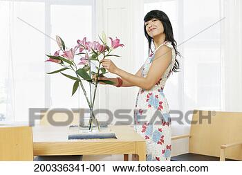 Stock Photography - woman arranging 
lilies in vase, 
smiling, side 
view. fotosearch 
- search stock 
photos, pictures, 
images, and photo 
clipart