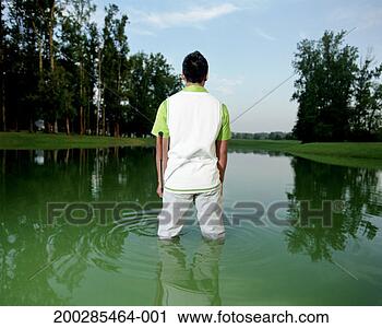 Stock Photography - young man holding 
golf club, standing 
in golf course 
pond, rear view. 
fotosearch - search 
stock photos, 
pictures, images, 
and photo clipart