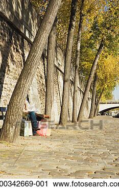 Stock Photography - couple on bench 
with shopping 
bags, heads obscured 
by tree trunk. 
fotosearch - search 
stock photos, 
pictures, images, 
and photo clipart