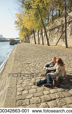 Stock Photography - france, paris, 
couple sitting 
on cobbled paving 
by river seine. 
fotosearch - search 
stock photos, 
pictures, images, 
and photo clipart