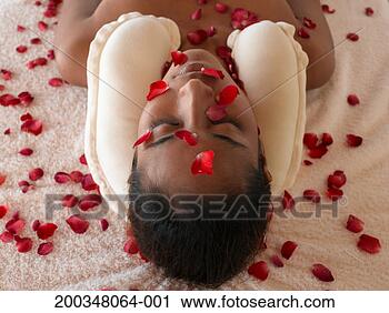 Stock Photography - woman lying on 
towel using neck 
cushion, petals 
scattered over 
face. fotosearch 
- search stock 
photos, pictures, 
images, and photo 
clipart