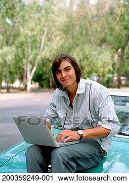 Stock Photography - young man sitting 
on car with laptop, 
smiling, portrait. 
fotosearch - search 
stock photos, 
pictures, images, 
and photo clipart