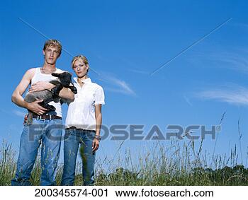 Stock Photography - young man and 
woman standing 
in field of tall 
grass, man holding 
lamb. fotosearch 
- search stock 
photos, pictures, 
images, and photo 
clipart