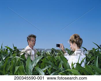 Stock Photography - young woman photographing 
young man in cornfield, 
smiling. fotosearch 
- search stock 
photos, pictures, 
images, and photo 
clipart