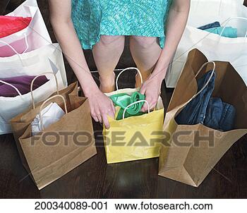 Stock Photography - young woman surrounded 
by shopping bags, 
looking at clothes 
in bag. fotosearch 
- search stock 
photos, pictures, 
images, and photo 
clipart