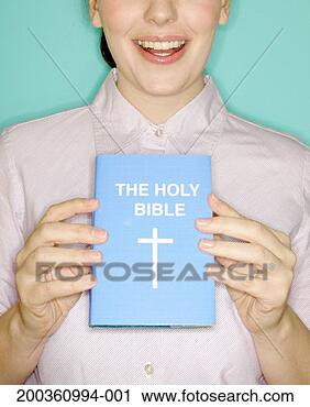 Stock Photography - young woman holding 
the 'holy bible', 
smiling, mid section. 
fotosearch - search 
stock photos, 
pictures, images, 
and photo clipart
