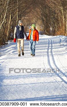 Stock Photography - mature couple 
walking down snow 
covered path, 
holding hands. 
fotosearch - search 
stock photos, 
pictures, images, 
and photo clipart