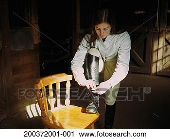 Stock Photography - teenage girl (17-19) 
in barn, tying 
boot. fotosearch 
- search stock 
photos, pictures, 
images, and photo 
clipart