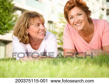 Stock Photography - two mature women 
lying on lawn 
smiling, portrait, 
surface level. 
fotosearch - search 
stock photos, 
pictures, images, 
and photo clipart