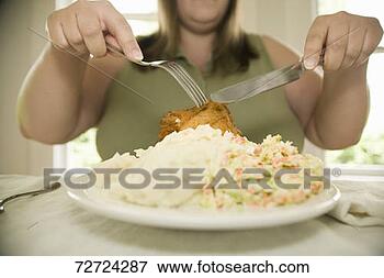 Picture - woman sitting 
at dining table, 
eating with fork 
and knife. fotosearch 
- search stock 
photos, pictures, 
images, and photo 
clipart