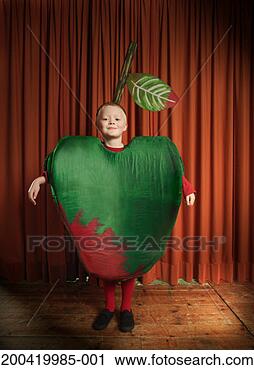 Stock Photography - boy (6-8) standing 
on stage wearing 
apple costume, 
smiling, portrait. 
fotosearch - search 
stock photos, 
pictures, images, 
and photo clipart