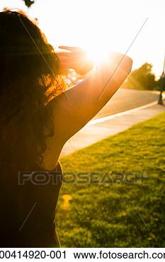Arquivo de Fotografia - jovem,   mulher, proteger, olhos,   sol, parte traseira. fotosearch - busca de fotos, imagens e clipart
