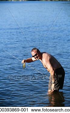 Stock Photography - man in lake with 
fishing pole, 
holding small 
perch, summer. 
fotosearch - search 
stock photos, 
pictures, images, 
and photo clipart
