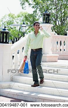 Stock Photography - man with shopping 
bags talking on 
cell phone, walking 
down stairs. fotosearch 
- search stock 
photos, pictures, 
images, and photo 
clipart