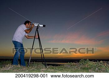 Stock Photography - man using telescope 
at dusk, side 
view. fotosearch 
- search stock 
photos, pictures, 
images, and photo 
clipart