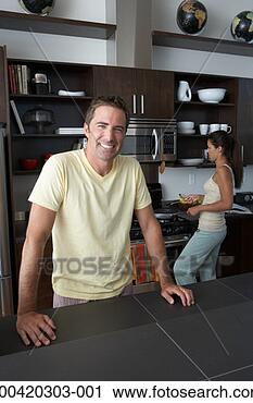 Stock Photography - man and woman 
preparing breakfast 
(focus on man 
in foreground). 
fotosearch - search 
stock photos, 
pictures, images, 
and photo clipart