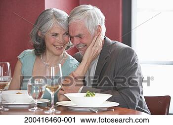 Stock Photography - mature man and 
woman laughing 
in restaurant, 
woman touching 
man's face. fotosearch 
- search stock 
photos, pictures, 
images, and photo 
clipart