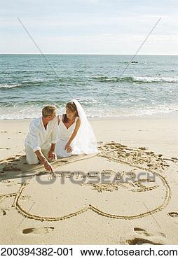 Stock Photography - mature newlyweds 
drawing heart 
on sand, saying 
'just married'. 
fotosearch - search 
stock photos, 
pictures, images, 
and photo clipart