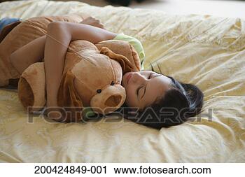 Stock Photography - teenage girl (15-17) 
lying on bed with 
stuffed animal. 
fotosearch - search 
stock photos, 
pictures, images, 
and photo clipart