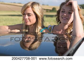 Stock Photography - two young women 
looking out of 
open sunroof of 
car, close-up. 
fotosearch - search 
stock photos, 
pictures, images, 
and photo clipart