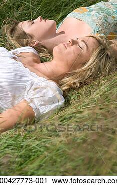 Stock Photography - two young women 
lying on long 
grass, eyes closed, 
close-up, side 
view. fotosearch 
- search stock 
photos, pictures, 
images, and photo 
clipart