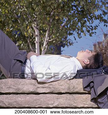 Stock Photography - young businessman 
lying on park 
bench, listening 
to mp3 player. 
fotosearch - search 
stock photos, 
pictures, images, 
and photo clipart