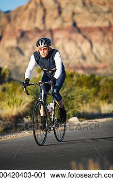 Stock Photography - young man riding 
bicycle down desert 
road. fotosearch 
- search stock 
photos, pictures, 
images, and photo 
clipart