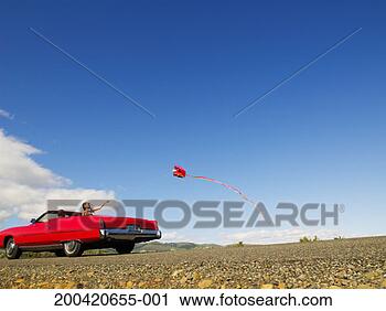 Stock Photography - young man and 
woman riding in 
convertible, woman 
flying kite. fotosearch 
- search stock 
photos, pictures, 
images, and photo 
clipart