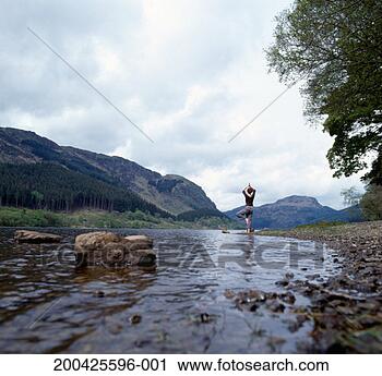 Stock Photography - young woman practising 
yogo at waters 
edge, rear view, 
ground view. fotosearch 
- search stock 
photos, pictures, 
images, and photo 
clipart