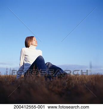 Stock Photography - young woman sitting 
in field, eyes 
closed, ground 
view. fotosearch 
- search stock 
photos, pictures, 
images, and photo 
clipart