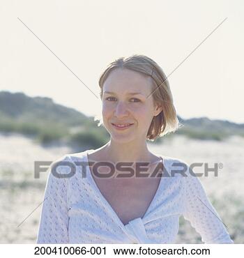 Stock Photography - young woman standing 
on beach, smiling, 
portrait (focus 
on woman). fotosearch 
- search stock 
photos, pictures, 
images, and photo 
clipart