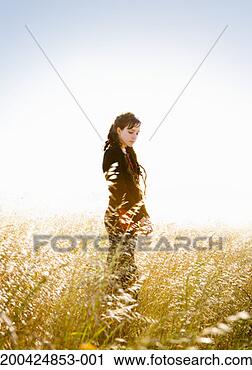 Stock Photography - young woman standing 
in tall grass, 
looking down. 
fotosearch - search 
stock photos, 
pictures, images, 
and photo clipart