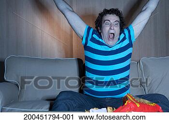 Stock Photography - man on sofa cheering 
in front of television. 
fotosearch - search 
stock photos, 
pictures, images, 
and photo clipart