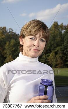 Picture - mature woman, 
 in white polo 
neck jumper,  
holding glass 
jar. fotosearch 
- search stock 
photos, pictures, 
images, and photo 
clipart