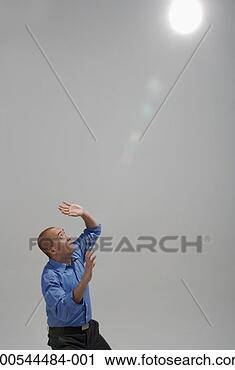Stock Photography - afraid businessman 
looking up at 
beam of light, 
studio shot. fotosearch 
- search stock 
photos, pictures, 
images, and photo 
clipart