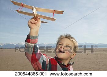 Stock Photography - boy (4-6) with 
toy airplane on 
beach at dawn, 
smiling, looking 
up. fotosearch 
- search stock 
photos, pictures, 
images, and photo 
clipart