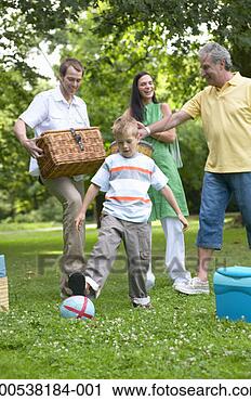 Stock Photography - boy (6-8) kicking 
ball in park with 
family carrying 
picnic things. 
fotosearch - search 
stock photos, 
pictures, images, 
and photo clipart