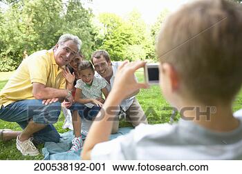 Stock Photography - boy (6-8) photographing 
family in park, 
rear view (focus 
on family). fotosearch 
- search stock 
photos, pictures, 
images, and photo 
clipart