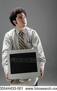 Stock Photography - businessman holding 
heavy computer 
monitor, studio 
shot. fotosearch 
- search stock 
photos, pictures, 
images, and photo 
clipart